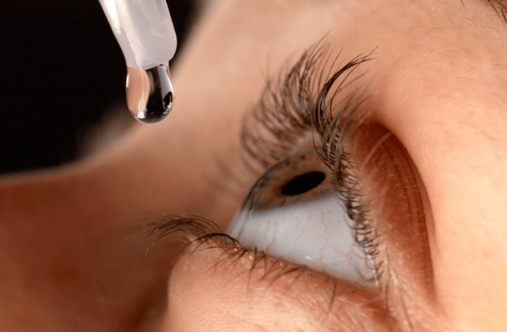 Close-up of an eye and Atropine eye drops being applied